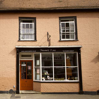 The Pearce's Pins shopfront on Ixworth High Street, with a dressmaker's dummy and vintage sewing machines in the window.