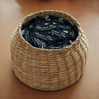 A woven basket filled with our "Pearce's Pins — Handmade in Suffolk" garment labels.